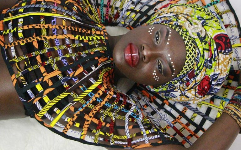 A black model wearing ankara piece and photographed while showing off while lying down